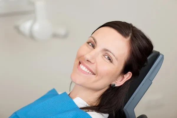 mujer sonriendo en su consulta al dentista