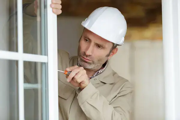 Hombre instalando ventana de forma sencilla siendo una de las aplicaciones del PVC más sencillas