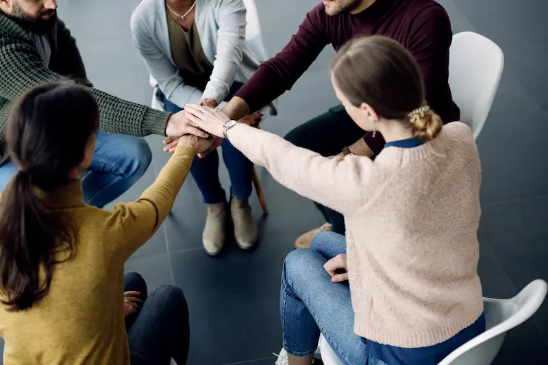 Participantes de la terapia de grupo juntando las manos